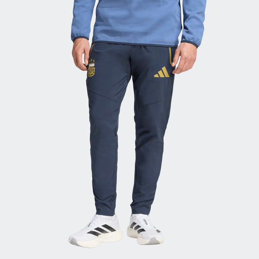 Adidas AFA Argentinië Travel Pants WK 2026 donker blauw met goud strepen en AFA-logo. Officiële voetbalbroek gedragen door de Argentijnse selectie tijdens reizen. kickoff antwerpen voetbalshop