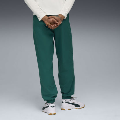 PUMA MANCHESTER CITY PUMATECH WOVEN PANTS 2025 2026 groen trainingsbroek met lichtblauw detail en clublogo van Manchester City op licht blauw achtergrond Kickoff Antwerpen voetbalshop football store