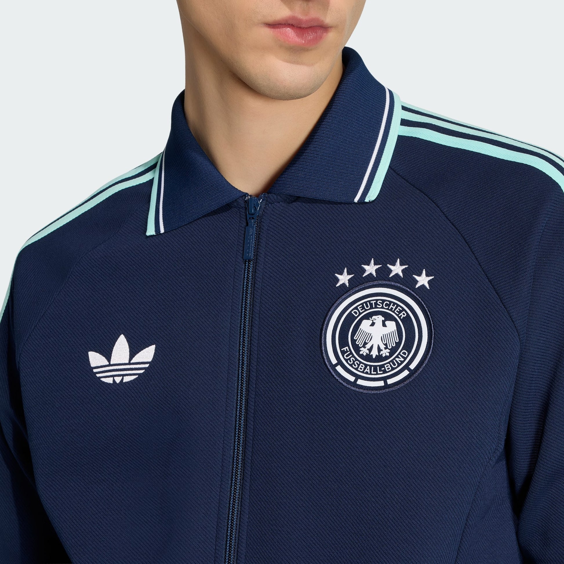 Witte Adidas Originals DFB Germany Anthem Jacket met zwart Trefoil-logo en Duitsland bondsembleem, verkrijgbaar bij voetbalshop Kickoff Antwerpen.