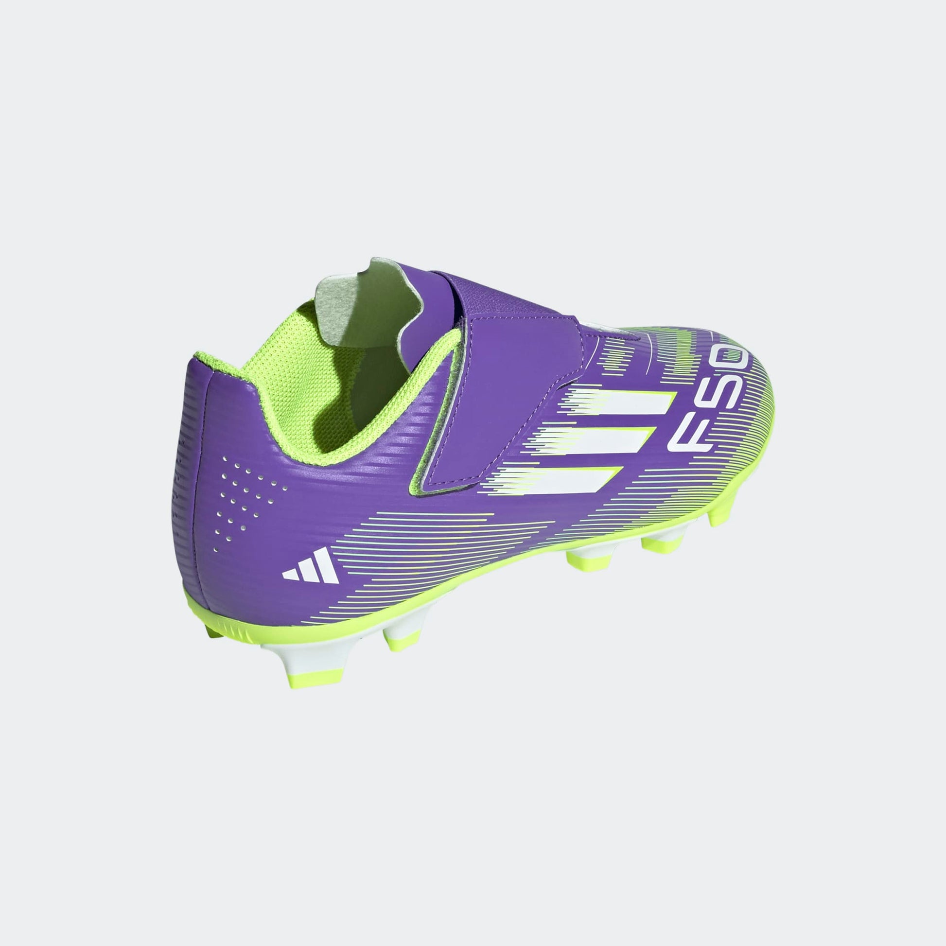 Adidas F50 Club Junior VEL FG/MG voetbalschoen met klittenband, paars/lyme design op een grasveld. Te koop bij Kickoff Antwerpen.