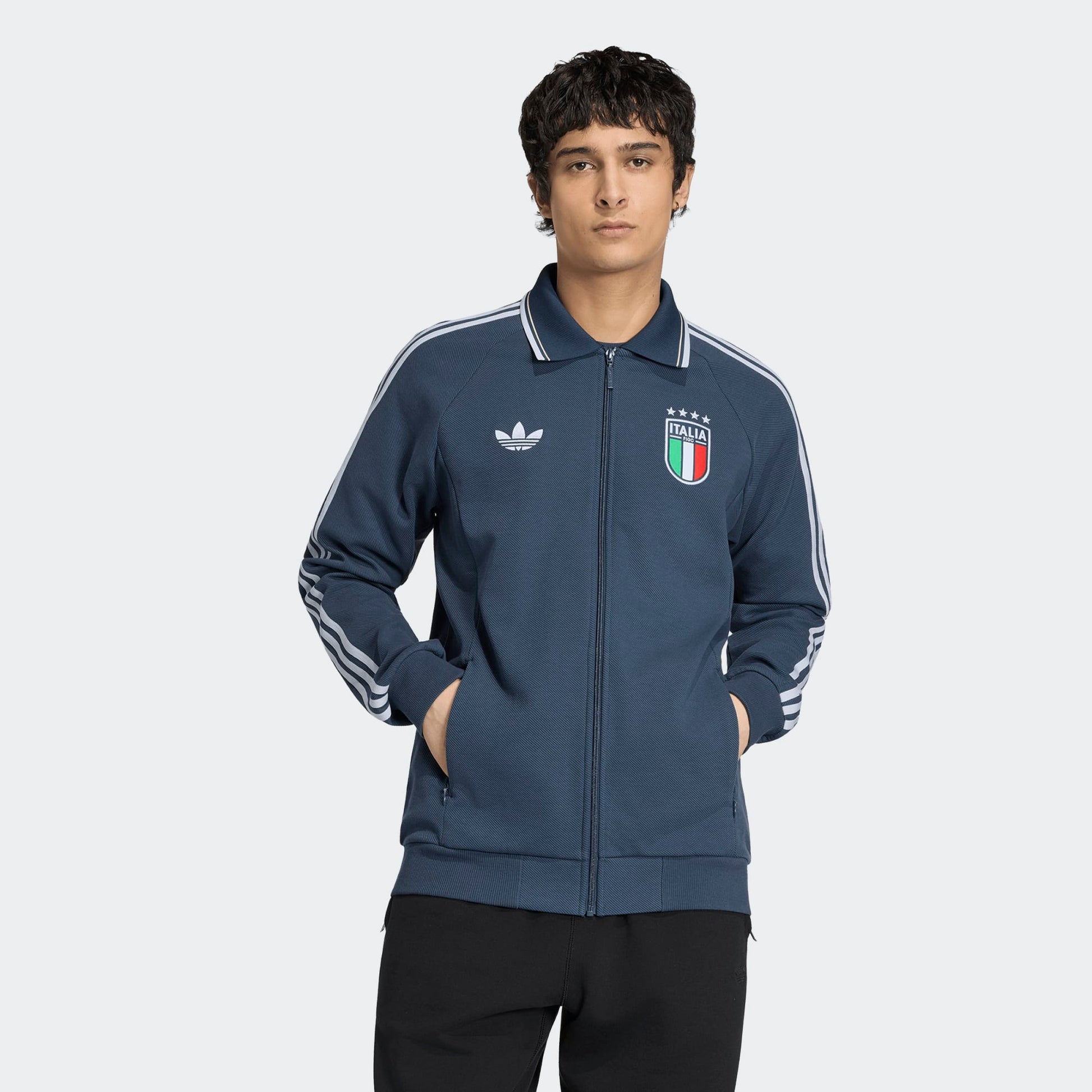Blauw Adidas Originals FIGC Italia Anthem Jacket met retro Italiaanse bondbadge en witte 3-Stripes, verkrijgbaar bij voetbalshop Kickoff Antwerpen.