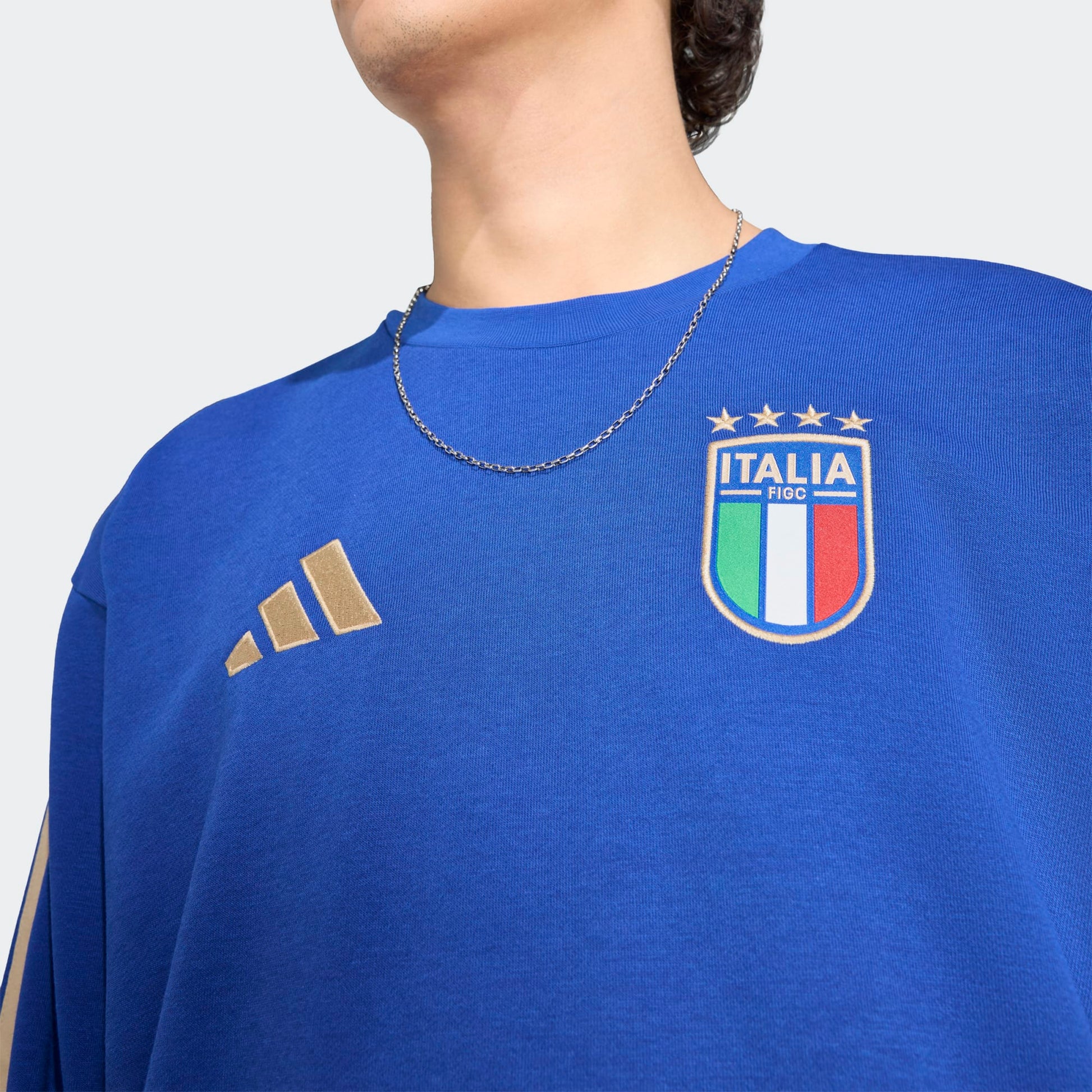 Adidas FIGC Italia DNA Sweat Top blauw met goud 3-Stripes en geborduurde Italiaanse voetbalbond (FIGC) badge. Beschikbaar bij voetbalshop Kickoff Antwerpen.