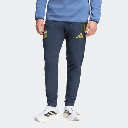 Adidas AFA Argentinië Travel Pants WK 2026 donker blauw met goud strepen en AFA-logo. Officiële voetbalbroek gedragen door de Argentijnse selectie tijdens reizen. kickoff antwerpen voetbalshop