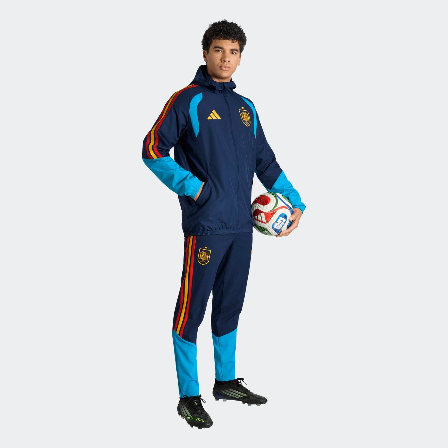 Adidas RFEF Spanje All-Weather Regenjas blauw met RFEF-logo en rode geel strepen WK 2026 collectie Kickoff Antwerpen voetbalshop