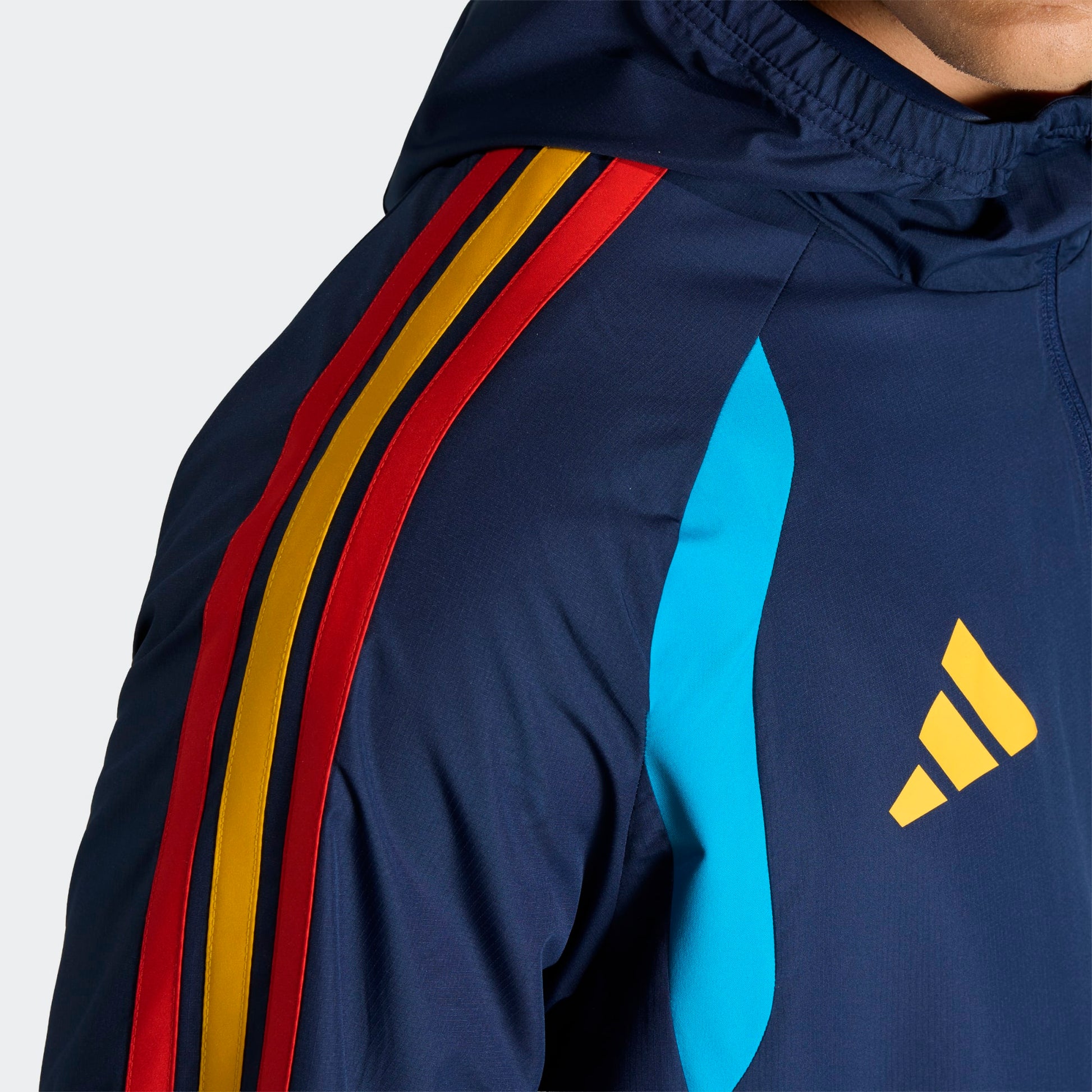 Adidas RFEF Spanje All-Weather Regenjas blauw met RFEF-logo en rode geel strepen WK 2026 collectie Kickoff Antwerpen voetbalshop