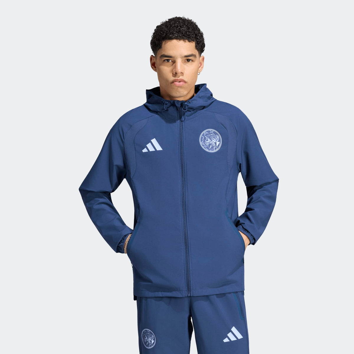 Adidas Ajax Amsterdam TT trainingspak 2026 2027 met clublogo en Adidas strepen op model Kickoff Antwerpen