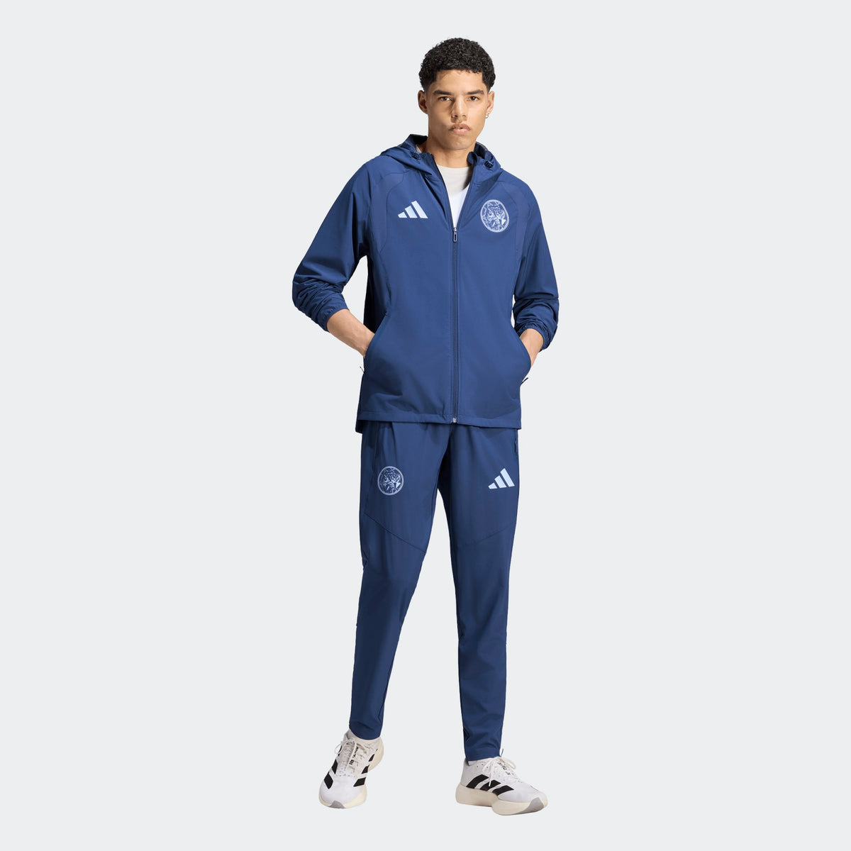 Adidas Ajax Amsterdam TT trainingspak 2026 2027 met clublogo en Adidas strepen op model Kickoff Antwerpen