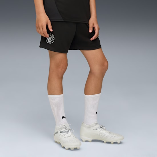 Puma Manchester City training short jeugd 2025 2026 met zakken en DryCELL logo, exclusief verkrijgbaar bij Kickoff Antwerpen, de voetbalshop van Antwerpen.