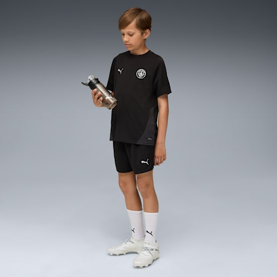 Puma Manchester City training short jeugd 2025 2026 met zakken en DryCELL logo, exclusief verkrijgbaar bij Kickoff Antwerpen, de voetbalshop van Antwerpen.